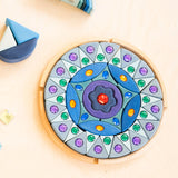 Grimms small sparkling mandala set in a circular wooden frame on a table next to wave shaped blocks