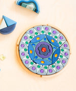 Grimms small sparkling mandala set in a circular wooden frame on a table next to wave shaped blocks