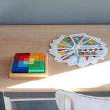Grimm's square creative set in a wooden storage display tray on a wooden desk next to an open ideas booklet.