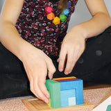 Child playing with the Grimm's square creative set in a wooden storage display tray.
