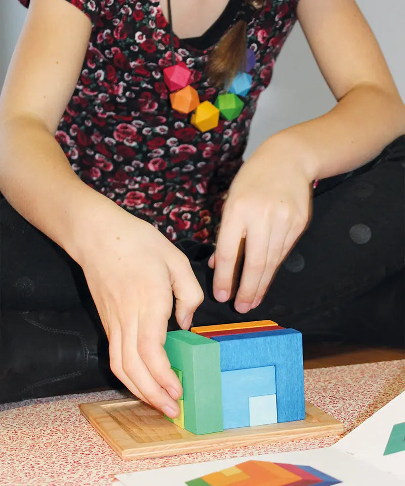 Child playing with the Grimm's square creative set in a wooden storage display tray.