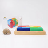 Side view of the Grimm's square creative set in a wooden storage display tray with a ideas booklet in the background.