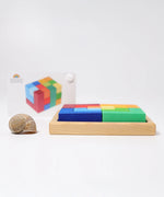 Side view of the Grimm's square creative set in a wooden storage display tray with a ideas booklet in the background.