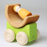 A green Grimm's stacking car with a mini rainbow piece and Grimm's friend wooden peg doll placed on top of it. These Grimm's toys are part of a wide range of wooden toys available here at Babipur. 