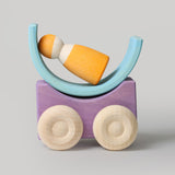 A purple Grimm's stacking car with a mini rainbow piece and Grimm's friend wooden peg doll placed on top of it. These Grimm's toys are part of a wide range of wooden toys available here at Babipur. 
