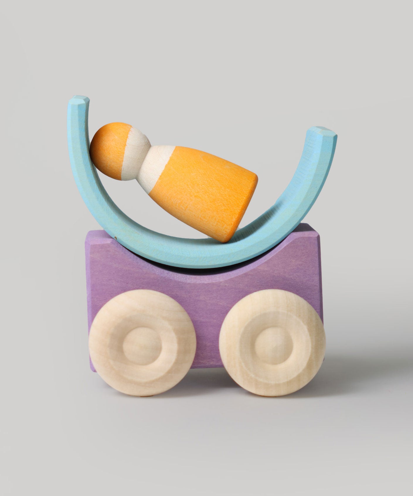 A purple Grimm's stacking car with a mini rainbow piece and Grimm's friend wooden peg doll placed on top of it. These Grimm's toys are part of a wide range of wooden toys available here at Babipur. 
