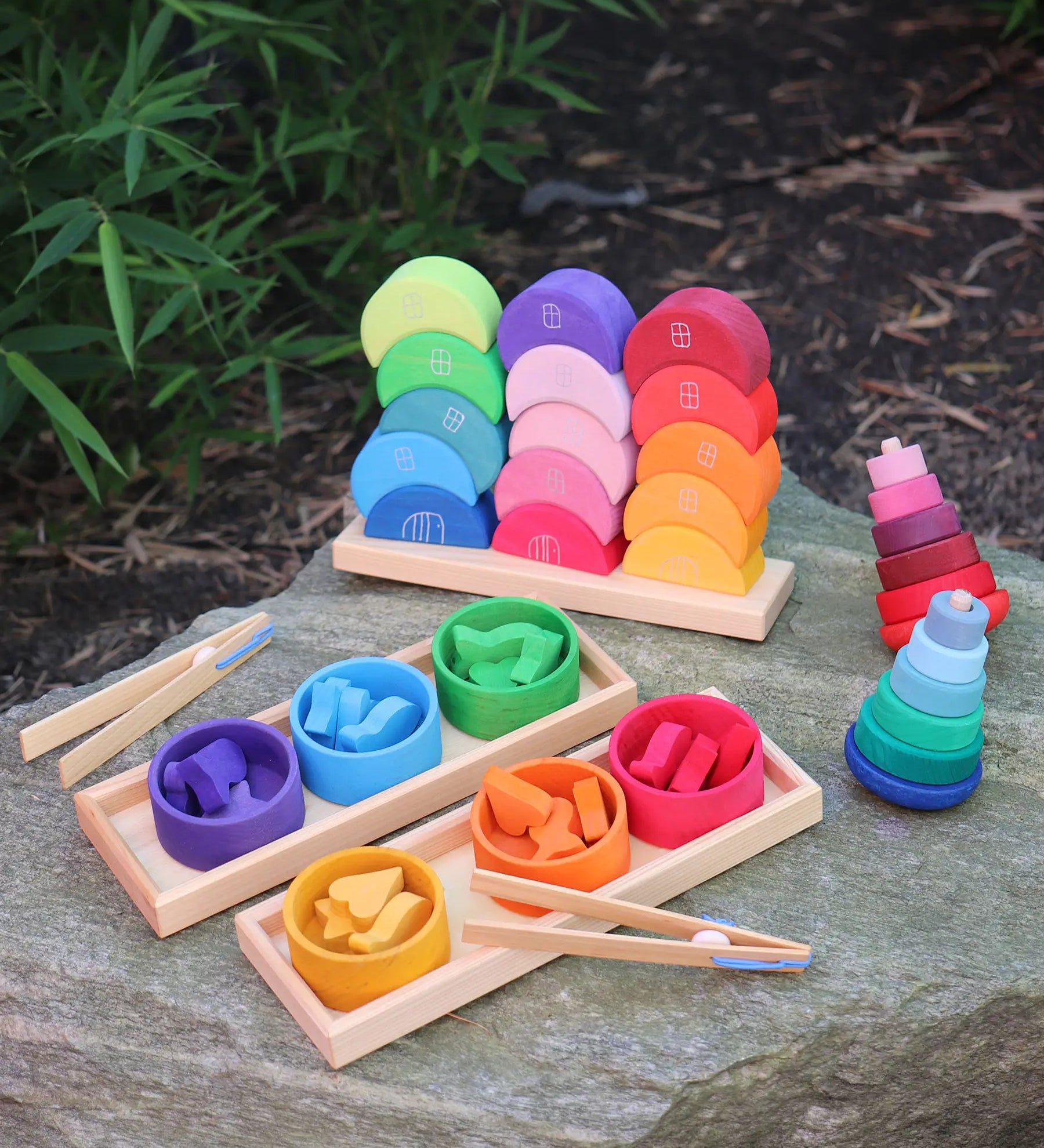 Grimms wooden stacking moon shapes houses displayed on a rock with a shape sorter set and 2 wobbly towers