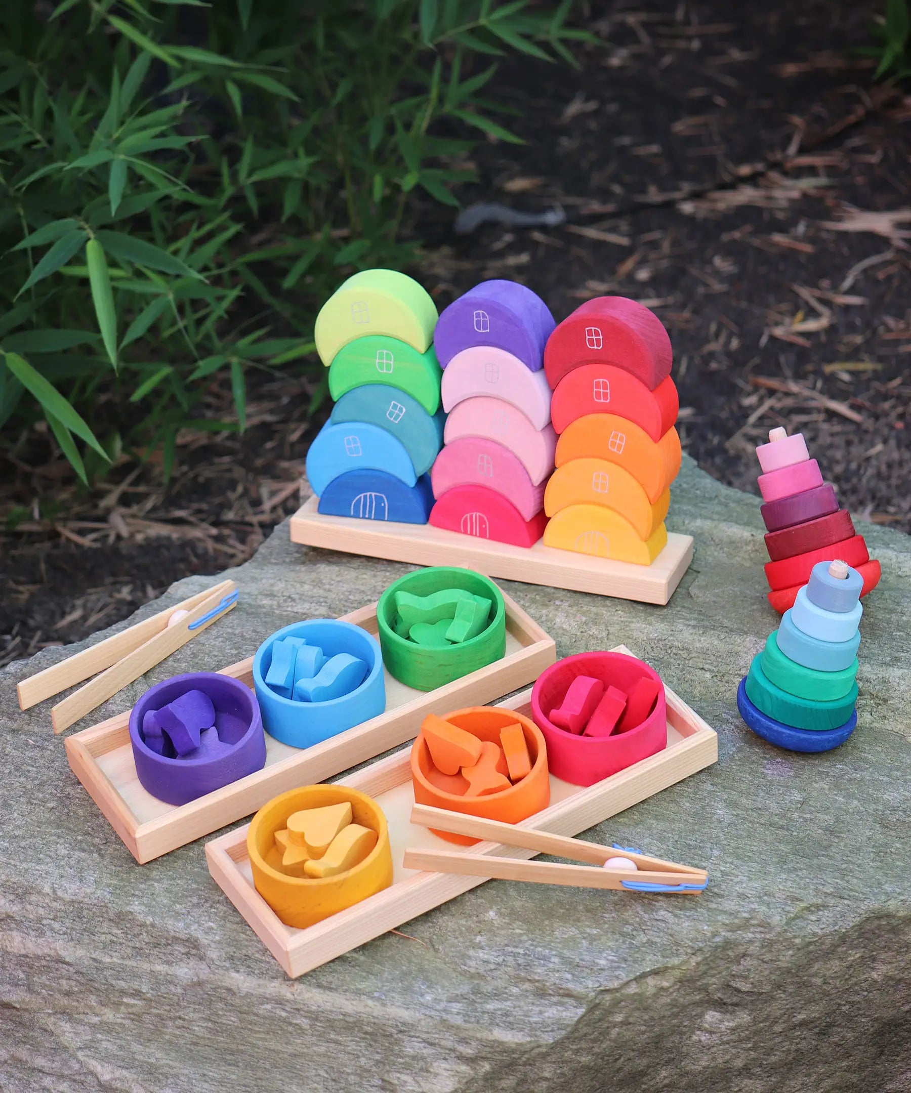 Grimms wooden stacking moon shapes houses displayed on a rock with a shape sorter set and 2 wobbly towers