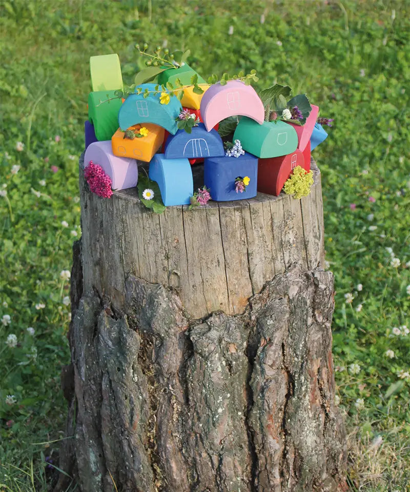 Looose Grimms wooden stacking moon shaped house pieces displayed on a tree stump