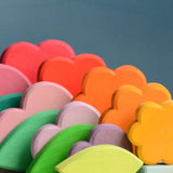 Grimms handcrafted wooden tower showing showing the loose flower, heart and cube pieces in rainbow and pastel palettes.