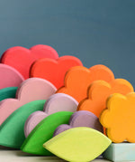 Grimms handcrafted wooden tower showing showing the loose flower, heart and cube pieces in rainbow and pastel palettes.