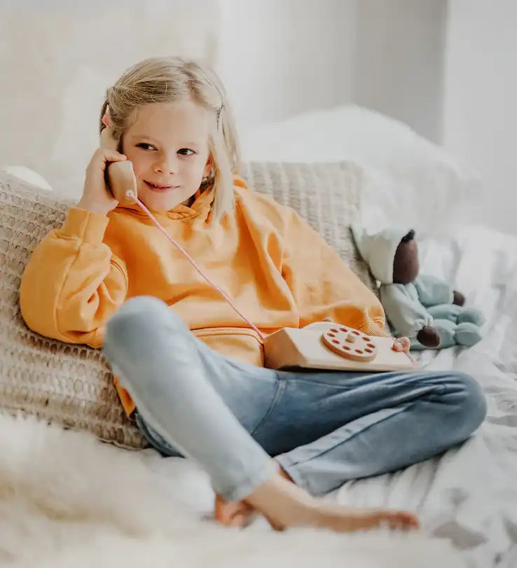 Child playing with the Grimm's wooden toy telephone. 