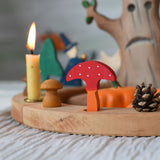 A Grimm's decorative toadstool figure placed on a natural celebration ring. A red coloured top with white dots and an orange coloured stalk