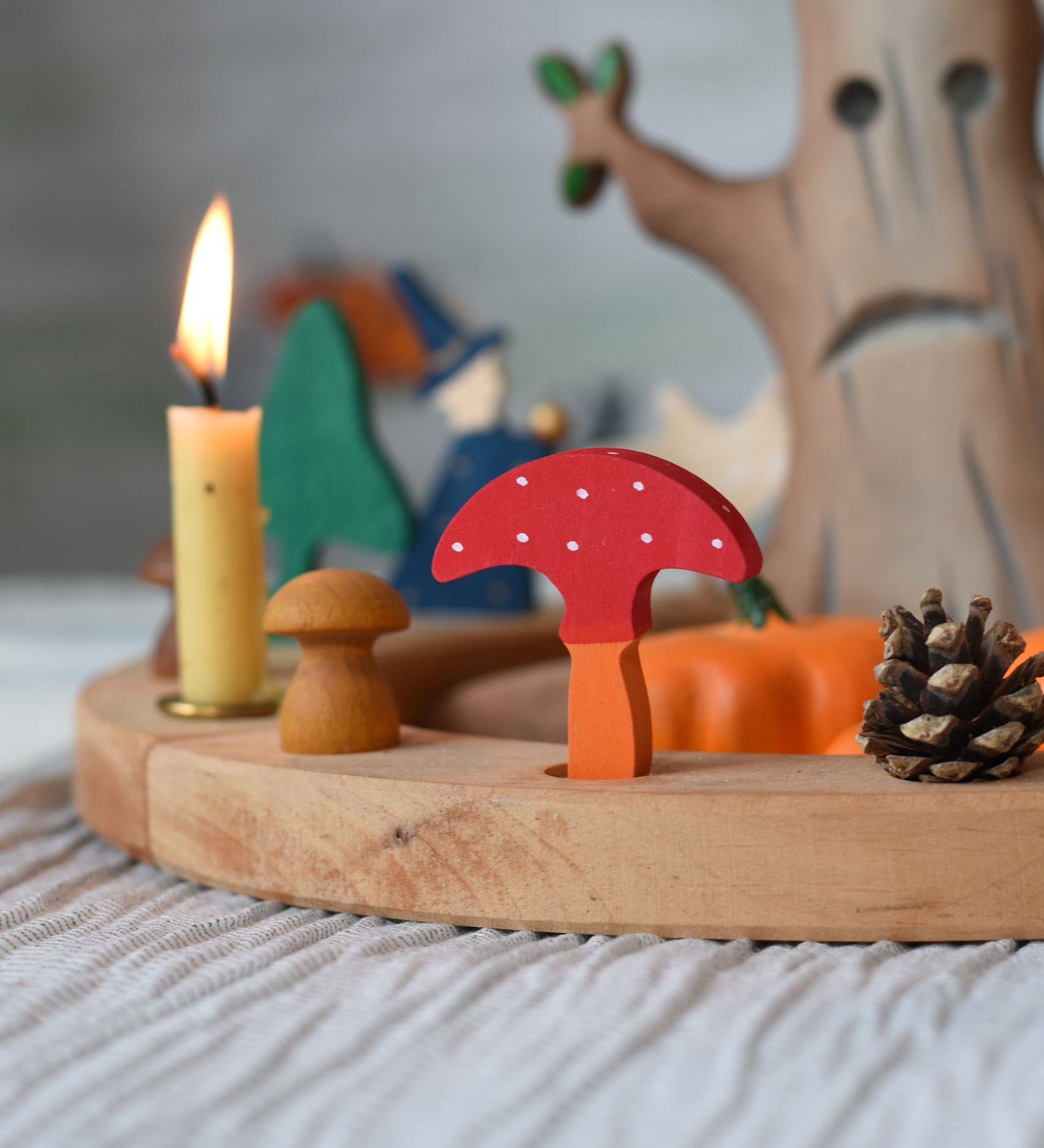 A Grimm's decorative toadstool figure placed on a natural celebration ring. A red coloured top with white dots and an orange coloured stalk