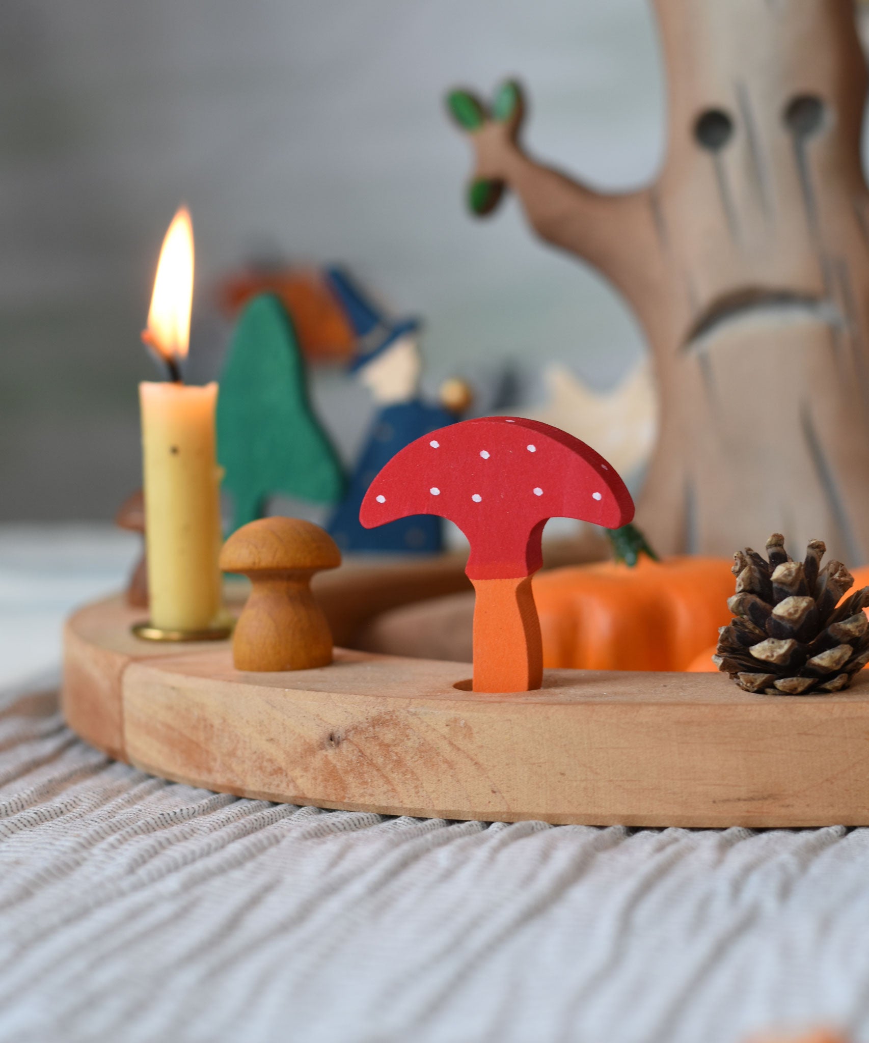 A Grimm's decorative toadstool figure placed on a natural celebration ring. A red coloured top with white dots and an orange coloured stalk