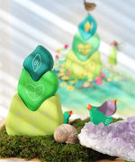 Grimm's tower leaves wooden stacking blocks set next to green and purple bird celebration ring figures.