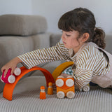 A child playing with the red Grimm's wooden stacking car toy driving it over a Grimm's rainbow piece. These Grimm's toys are part of a wide range of wooden toys available here at Babipur. 
