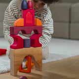 A child playing with the Grimm's red car stacking puzzle building block set stacking blocks on top of each other with Grimm's friends on top. These Grimm's toys are part of a wide range of wooden toys available here at Babipur. 