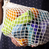Grimm's tree slices wooden coloured building blocks in their netting storage bag. 