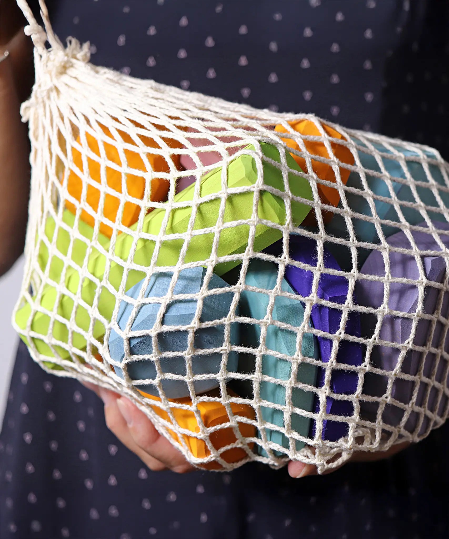 Grimm's tree slices wooden coloured building blocks in their netting storage bag. 