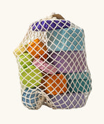 Grimm's tree slices wooden coloured building blocks in their netting storage bag. 