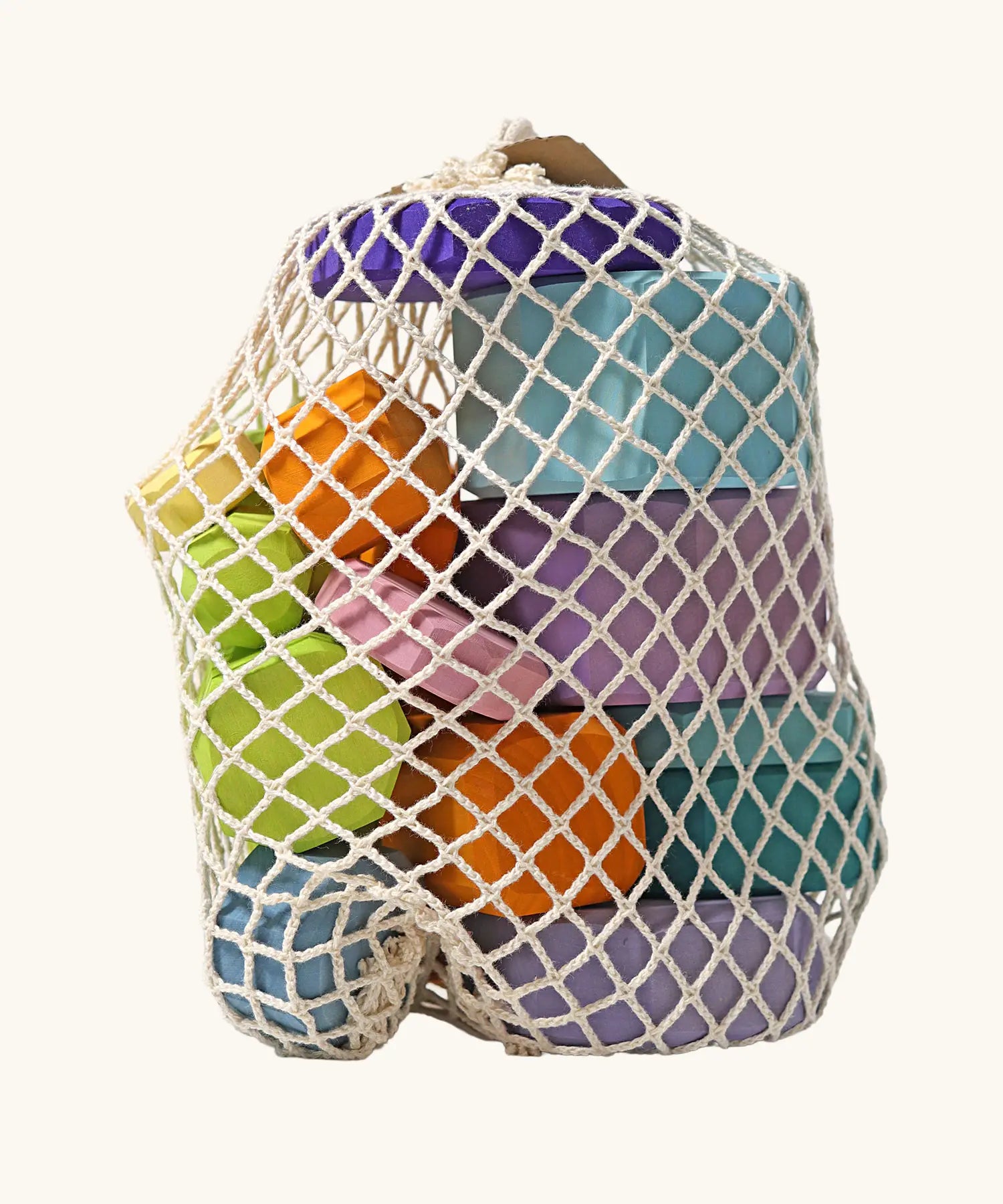 Grimm's tree slices wooden coloured building blocks in their netting storage bag. 