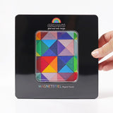 A adult hand holding a closed tin with a clear window displaying the Grimm's triangle magnetic set