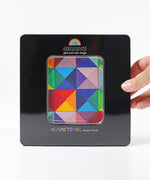 A adult hand holding a closed tin with a clear window displaying the Grimm's triangle magnetic set