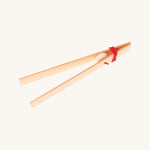 Grimms wooden tweezers on a cream background.