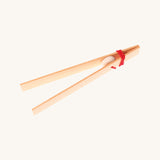 Grimms wooden tweezers on a cream background.
