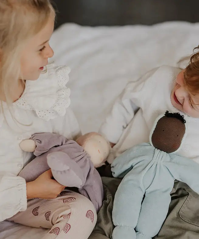 Children playing with a violet and aqua Grimms soft Waldorf dolls