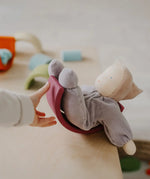 Child hand pushing a Grimms soft violet waldorf doll on a wooden rainbow arch piece