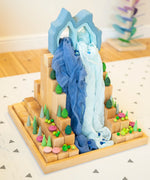 A waterfall play scene using Grimms natural blocks, pastel forest set, play cloth and other loose wooden pieces.