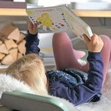Child lying on a Wobbel board an reading the pages from the Grimm's weather book 