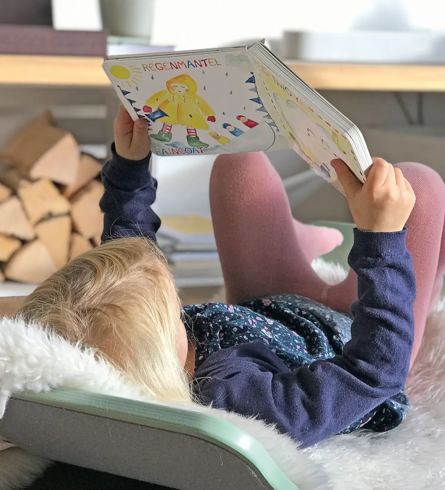 Child lying on a Wobbel board an reading the pages from the Grimm's weather book 