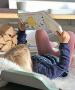 Child lying on a Wobbel board an reading the pages from the Grimm's weather book 
