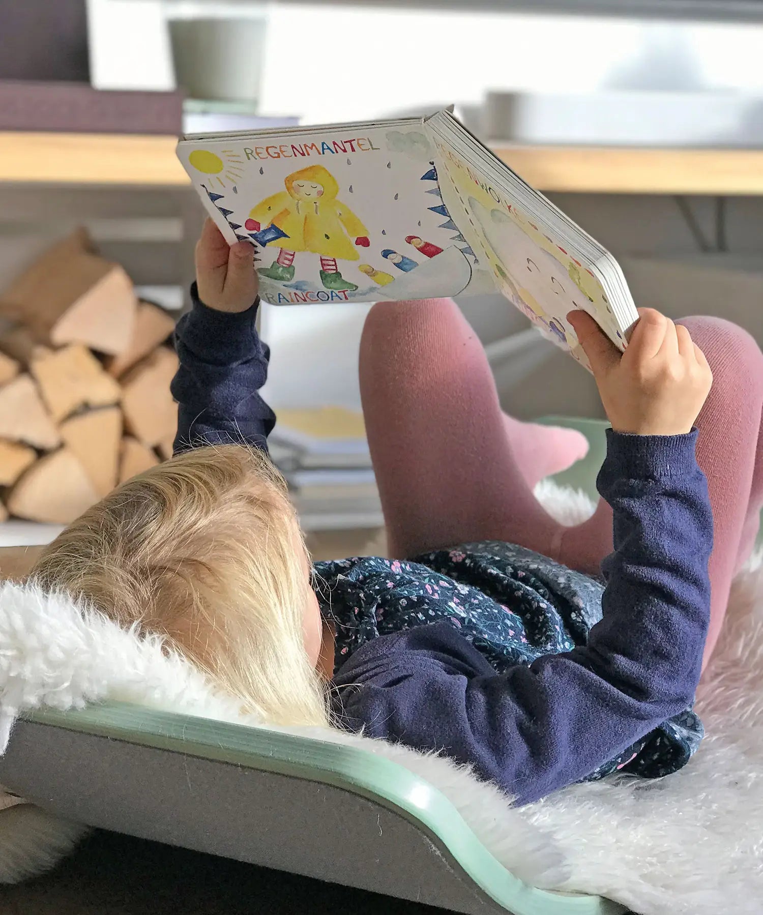 Child lying on a Wobbel board an reading the pages from the Grimm's weather book 