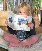 Child sitting on a Wobbel board an reading the pages from the Grimm's weather book 