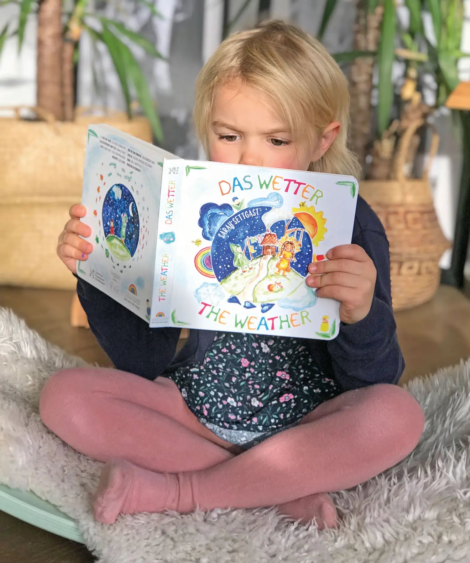 Child sitting on a Wobbel board an reading the pages from the Grimm's weather book 