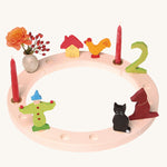 Grimm's 16-Hole White Celebration Ring on a plain background with decorative figures. 