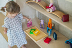 A child playing with the Grimm's Windows Building & Stacking Set stacking pieces on top of each other. These Grimm's toys are part of a wide range of wooden toys available here at Babipur. 