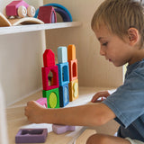 A child playing with the Grimm's Windows Building & Stacking Set. The child is stacking them on top of each other and inserting the shapes into the window frames. These Grimm's toys are part of a wide range of wooden toys available here at Babipur. 