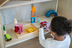 A child playing with the Grimm's Windows Building & Stacking Set. The child is holding the purple coloured window piece in their hand taking the shaped inset out of the window frame. These Grimm's toys are part of a wide range of wooden toys available here at Babipur. 