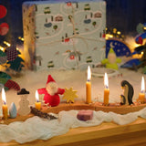 A festive Christmas display with Grimm's celebration ring pieces, a snowman and penguin family decorative figures and bearded dwarf dolls