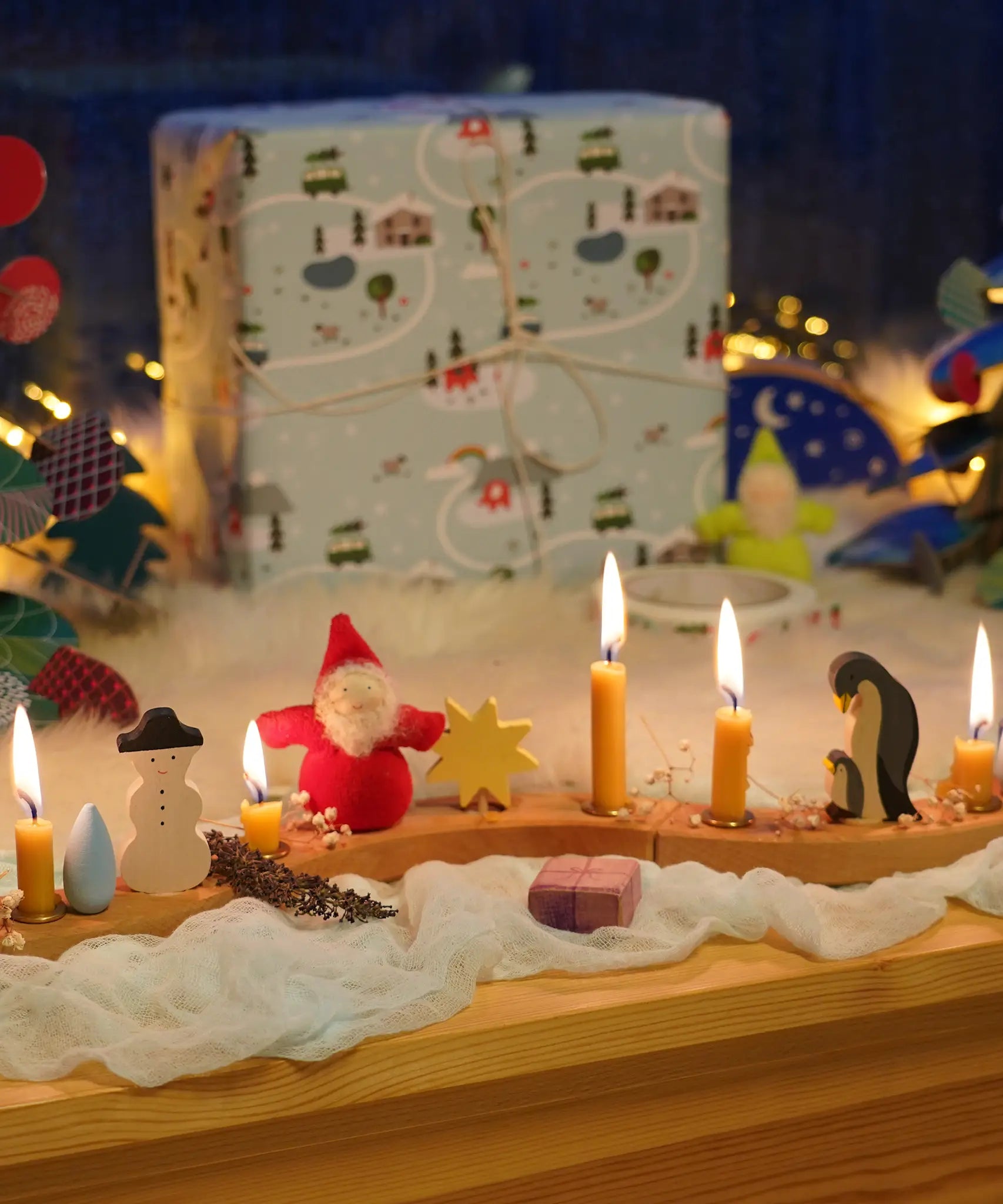A festive Christmas display with Grimm's celebration ring pieces, a snowman and penguin family decorative figures and bearded dwarf dolls