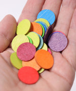 A close up of some Grimm's Rainbow Confetti Dots in an adult's hand. 