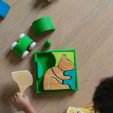 An overhead view of a child playing with the Grimm's green squirrel Building Set. Wooden blocks in various shades of green and natural wood in a green coloured wooden storage tray. These Grimm's toys are part of a wide range of wooden toys available here at Babipur. 