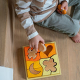 A child playing with the Grimm's Building Set in Yellow. Wooden blocks in various shades of yellow and natural wood in a yellow coloured wooden storage tray. These Grimm's toys are part of a wide range of wooden toys available here at Babipur. 