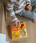 A child playing with the Grimm's Building Set in Yellow. Wooden blocks in various shades of yellow and natural wood in a yellow coloured wooden storage tray. These Grimm's toys are part of a wide range of wooden toys available here at Babipur. 