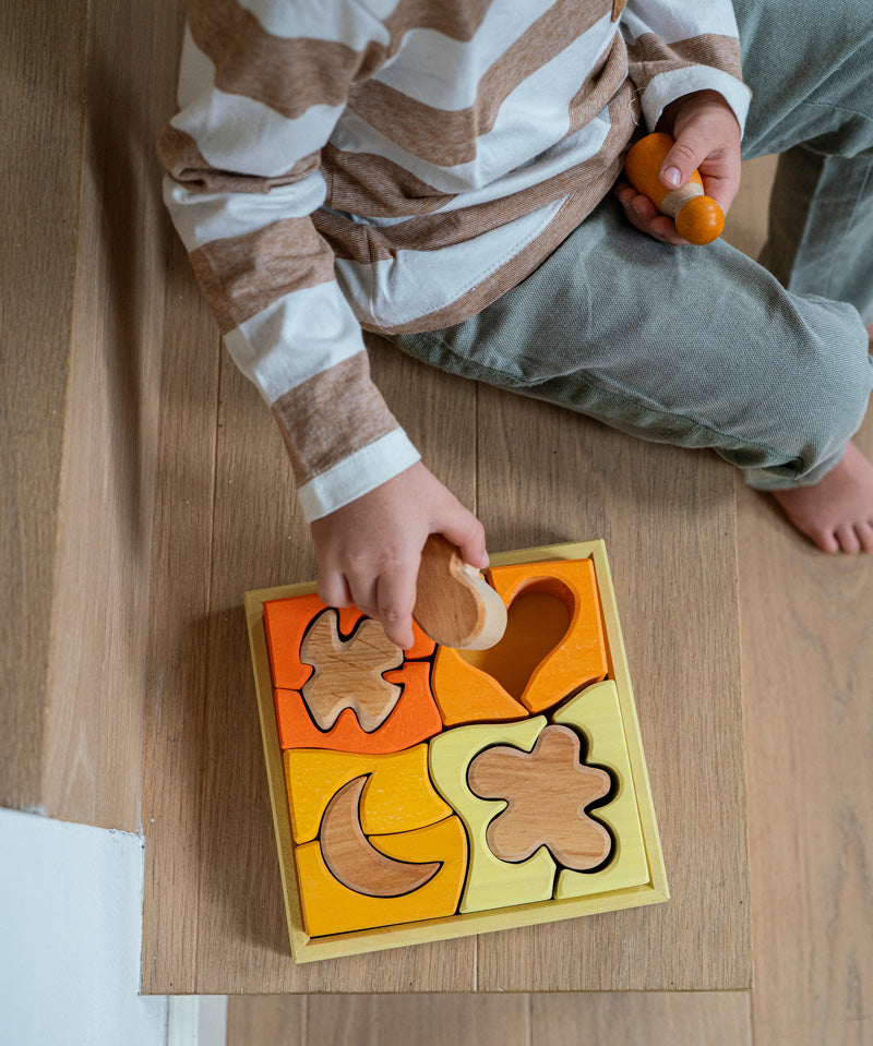 A child playing with the Grimm's Building Set in Yellow. Wooden blocks in various shades of yellow and natural wood in a yellow coloured wooden storage tray. These Grimm's toys are part of a wide range of wooden toys available here at Babipur. 
